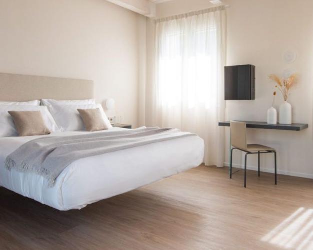 Camera moderna con letto sospeso e arredi minimalisti, luce naturale e pavimento in legno.